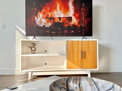a white entertainment center with a fire painting on the wall at Top Floor Hollywood 1BR Condo with Views in Los Angeles