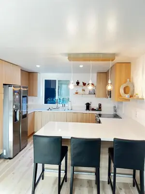 a kitchen with a large white counter and chairs at 6 miles from Disney, Book your dream vacations! in Fullerton