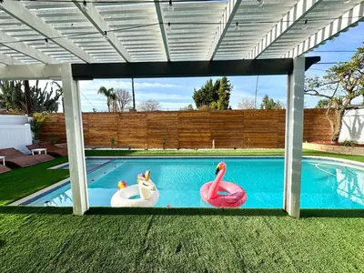 a swimming pool with two flamingos in the middle at 4 Bed Modern Pool House with Spa & Game Room in Northridge Hospital Heliport