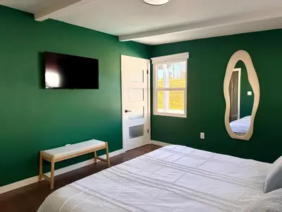 a bedroom with a green wall with a bed and a mirror at 4 Bed Modern Pool House with Spa & Game Room in Northridge Hospital Heliport