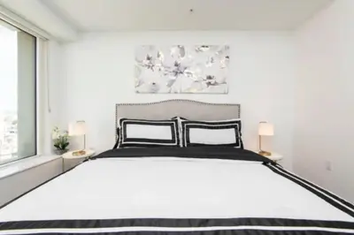 a white bedroom with a large bed with two lamps at Modern 3 Bedroom High-Rise with resort Pool in Los Angeles