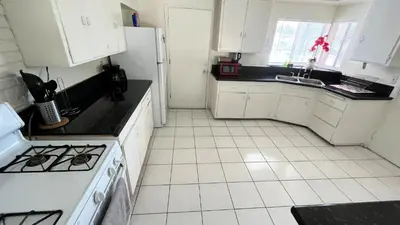 a kitchen with white cabinets and a stove top oven at The Disney Hostel - Fullerton - OC in Fullerton