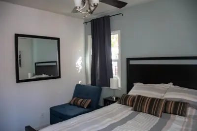a bedroom with a bed and a mirror and a chair at Cozy and Relaxing in Suburbs of LA in Mission Hills