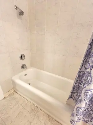 a white tub in a bathroom with a blue and white shower curtain at Spacious 5BR Private Home 5 minutes to Rodeo Drive with Hot Tub Spacious Backyard Parking in Los Angeles