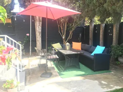 a patio with a couch and a table with a red umbrella at 4bed 2ba Hollywood house Block away from sunset, Free parking, private backyard in Los Angeles