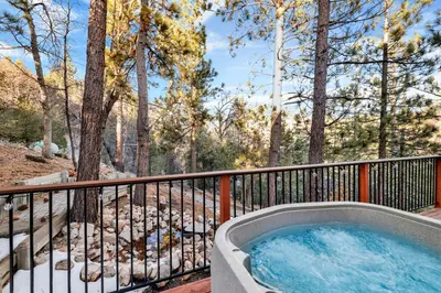 a hot tub on a balcony with trees at High-Top Lakeview Chateau Relaxing Modern Fawnskin Retreat in Fawnskin