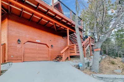 a house with a wooden garage door and a staircase at High-Top Lakeview Chateau Relaxing Modern Fawnskin Retreat in Fawnskin