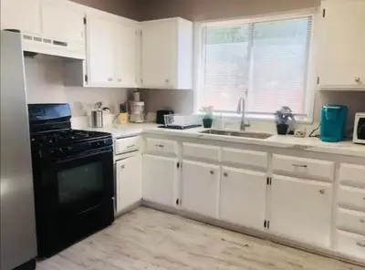a kitchen with white cabinets and a black stove at 4bed 2ba Hollywood house Block away from sunset, Free parking, private backyard in Los Angeles