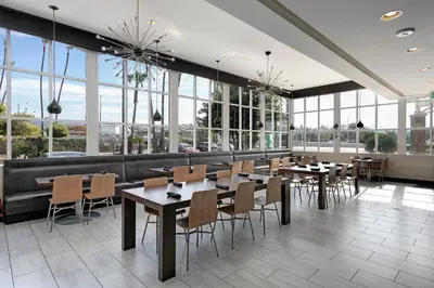 a restaurant with tables and chairs and large windows at Pacific Stay Hotel in West Covina