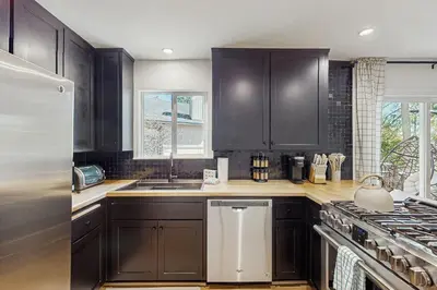a kitchen with black cabinets and a white refrigerator at Arrowhead Aura in Lake Arrowhead
