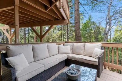 a white couch sitting on a deck with a table at Cozy Owl Lodge, Central AC & Hea, Spa Tub & BBQ in Lake Arrowhead