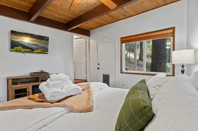 a bedroom with a white bed with towels on it at Cozy Owl Lodge, Central AC & Hea, Spa Tub & BBQ in Lake Arrowhead