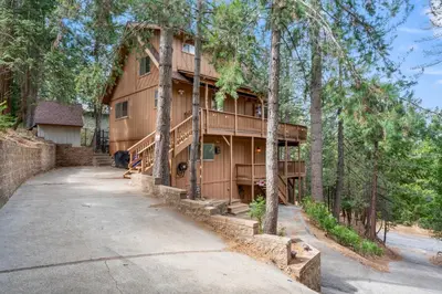 a large wooden house with a driveway at Cozy Owl Lodge, Central AC & Hea, Spa Tub & BBQ in Lake Arrowhead