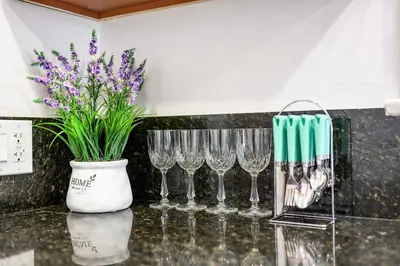 a group of wine glasses and a vase with purple flowers at Comfortable Home Near LA with Full Kitchen & Laundry in Alhambra