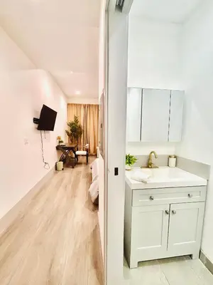 a white kitchen with a sink and a living room at New Lux Skyline Loft in LA in North Sherman Way