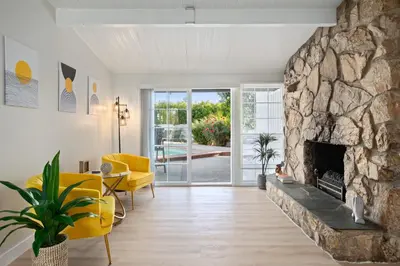 a living room with a stone fireplace and yellow chairs at Sunny SoCal Escape 3BR 2BA Bright home with pool in Winnetka