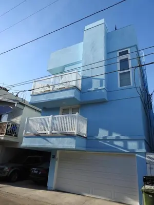 a blue house with a balcony and a garage at Luxe 2-BR with King suite, rooftop, steps from beach in Los Angeles