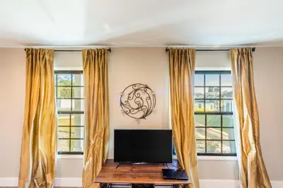 a living room with windows and a flat screen tv at Spacious 4BR Retreat near Disneyland & Beaches in Placentia
