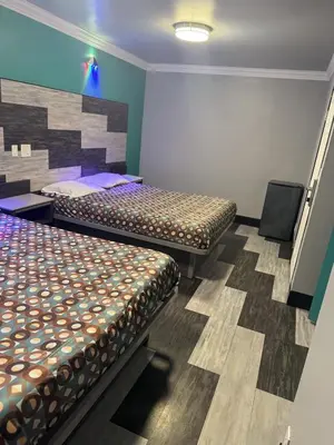 a room with two beds and a chair in it at Bob's Motel in Commerce