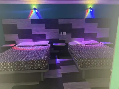 two beds in a room with purple lights at Bob's Motel in Commerce