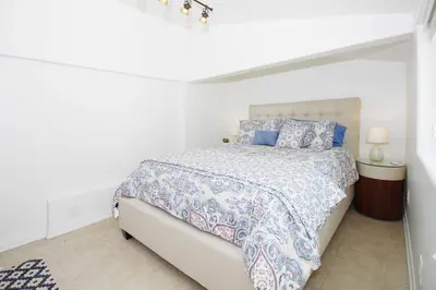 a white bedroom with a bed with blue and white sheets at In The Village With Private Entrance in Claremont