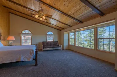 a bedroom with a bed and a couch and windows at Valley View Cabin in Big Bear Lake