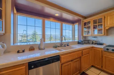 a kitchen with wooden cabinets and a large window at Valley View Cabin in Big Bear Lake