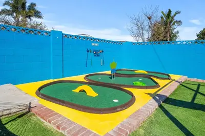 a miniature golf course in a yard with a blue wall at Mickeys House by OC Adventure Homes in Anaheim