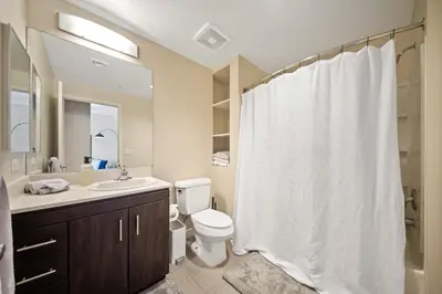 a bathroom with a white shower curtain and a toilet at Chic 1BR Retreat with Pool, Gym & Jacuzzi in Mid Wilshire & Miracle Mile in Los Angeles