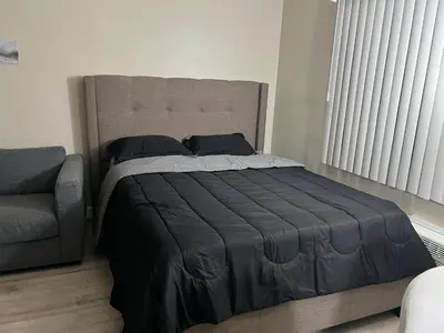 a bedroom with a bed and a chair and a window at NoHo Cozy Cove in Burbank