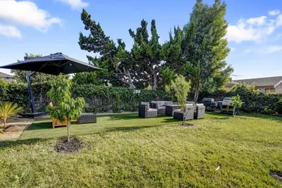 a yard with chairs and an umbrella at The Pacific Nest - 10min from LAX in Hawthorne