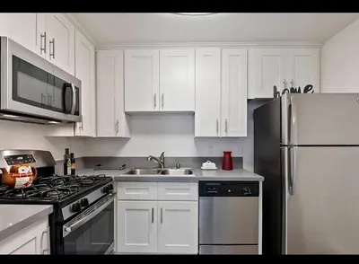 a kitchen with white cabinets and a stainless steel refrigerator at 2-Bedroom Hollywood Apartment in Los Angeles