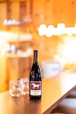 a bottle of wine sitting on a table with a glass at BunkHouse 1960's Camp Vibe with Timeless Wet Bar in Springville