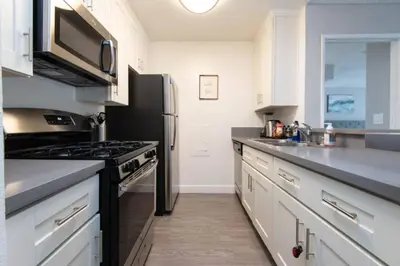 a kitchen with white cabinets and a black refrigerator at Snazzy 2Bd Apartment Rooftop Pool & Iconic Hollywood Sign Views in Los Angeles