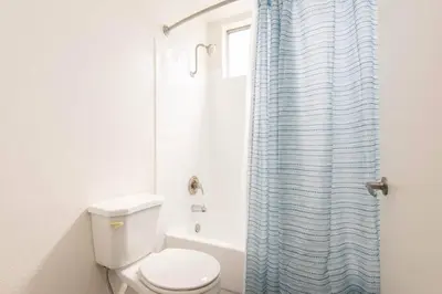 a bathroom with a toilet and a blue shower curtain at Snazzy 2Bd Apartment Rooftop Pool & Iconic Hollywood Sign Views in Los Angeles