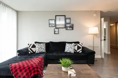 a living room with a black couch with pillows at Snazzy 2Bd Apartment Rooftop Pool & Iconic Hollywood Sign Views in Los Angeles