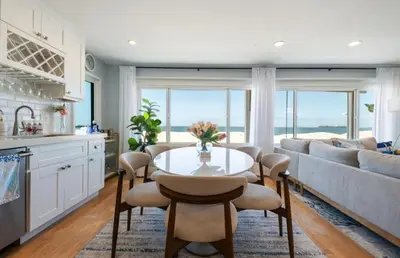 a kitchen and living room with a table and a couch at Sea La Vie Beachhouse on the sand in Long Beach