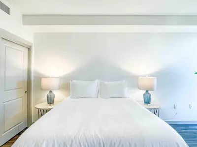 a bedroom with a large white bed with two lamps at Studio Downtown Walk to Convention Center in Los Angeles