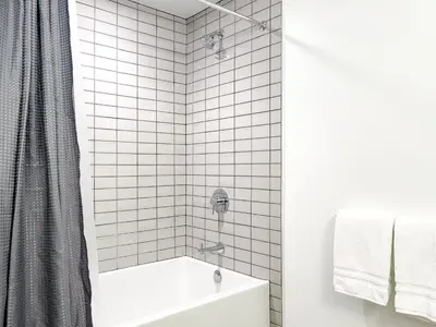 a white tiled bathroom with a tub and a shower at Suite Downtown Pool and Gym Access in Los Angeles