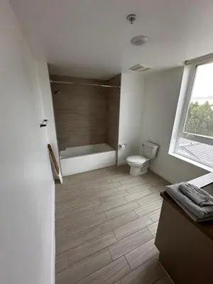 a bathroom with a tub and a toilet and a window at Modern Unit Near Glendale Galleria and Walk to Shopping & Dining! in Glendale