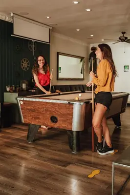 two women playing pool in a room with a pool table at Samesun Hollywood Hotel & Hostel in Los Angeles