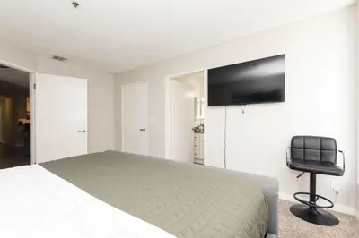 a bedroom with a bed and a chair and a television at Hollywood Luxe 2BR Apartment with Rooftop Pool and Breathtaking Views in Los Angeles