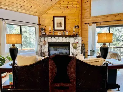 a living room with a fireplace and a table and chairs at ADELAIDE HILL IN PINE MOUNTAIN CLUB BREATHTAKING VIEWS 3Bd 3Bth SPA TUB in Pine Mountain Club