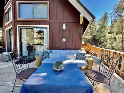 a patio with a blue table and chairs and a house at ADELAIDE HILL IN PINE MOUNTAIN CLUB BREATHTAKING VIEWS 3Bd 3Bth SPA TUB in Pine Mountain Club