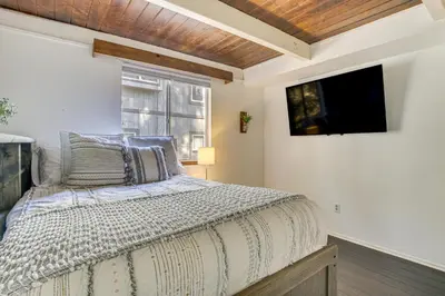 a bedroom with a bed and a tv on the wall at Family-Friendly Lake Arrowhead Cabin with Game Room! in Lake Arrowhead