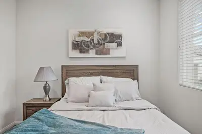 a bedroom with a bed and a table with a lamp at Gorgeous Family Home, Close to Frwys, Hospitals & Sports Arenas, Pets OK in Orange