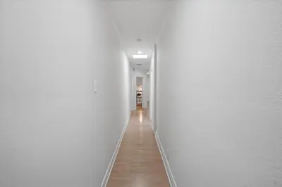 a long hallway with white walls and a wooden floor at Foosball l LA Mural l DTLA l UnivStudios l BevHills in Glendale