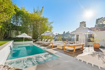 a pool with chairs and umbrellas in a backyard at Casa Cortona by Stay Awhile Villas in Los Angeles