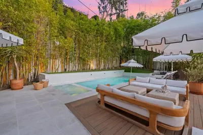 a backyard with a swimming pool with white furniture and trees at Casa Cortona by Stay Awhile Villas in Los Angeles