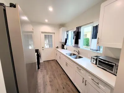 a white kitchen with a sink and a microwave at Perfectly located Pico Robertson ground floor 3 bedroom apartment Walk to restaurants WIFI TV Game Console Parking 5 minutes to Rodeo Drive in Los Angeles